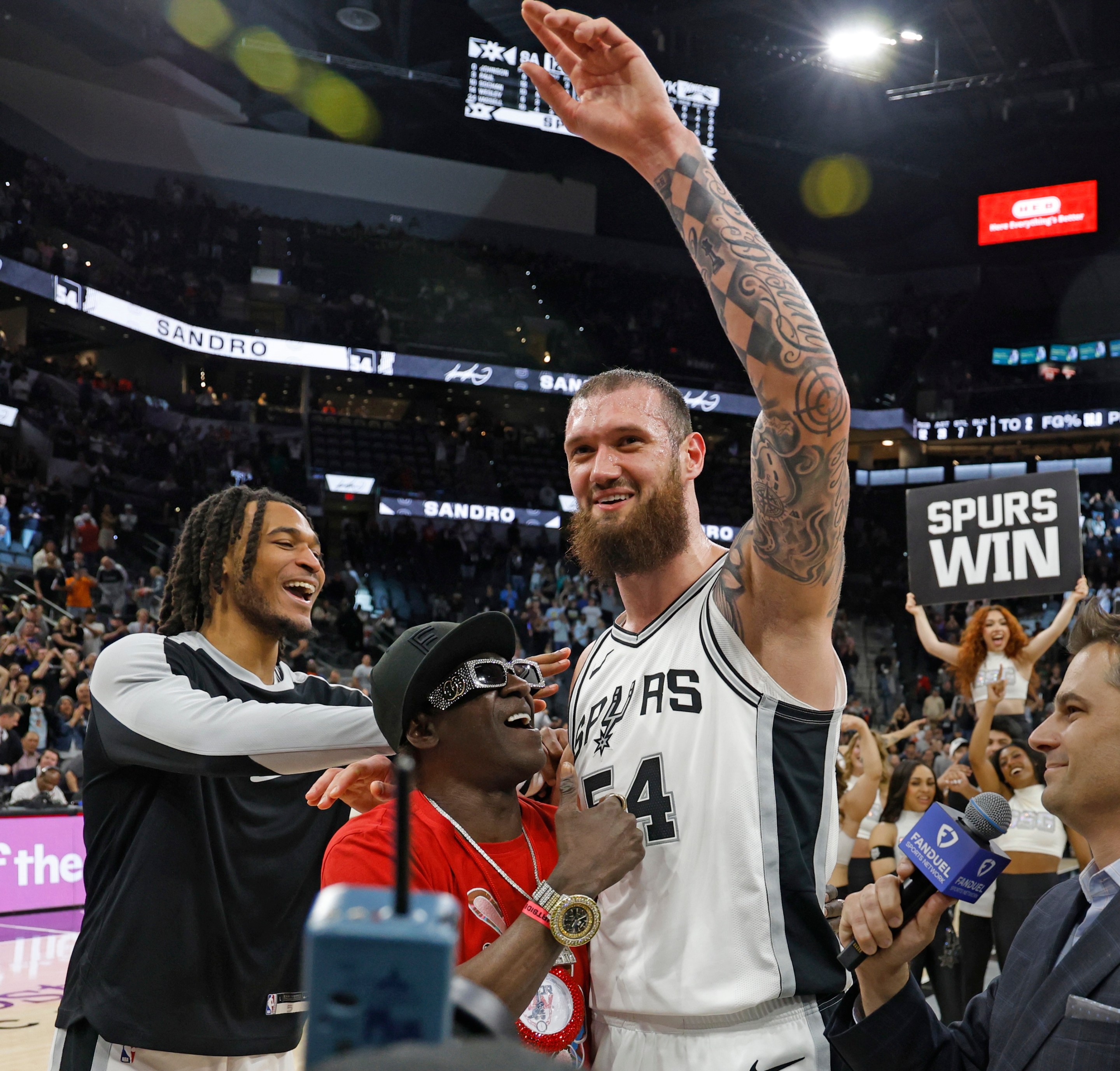 Sandro Mamukelashvili #54 of the San Antonio Spurs is joined by teammate Stephon Castle #5 and Flavor Fav at the end of the game against the New York Knicks at Frost Bank Center on March 19, 2025.